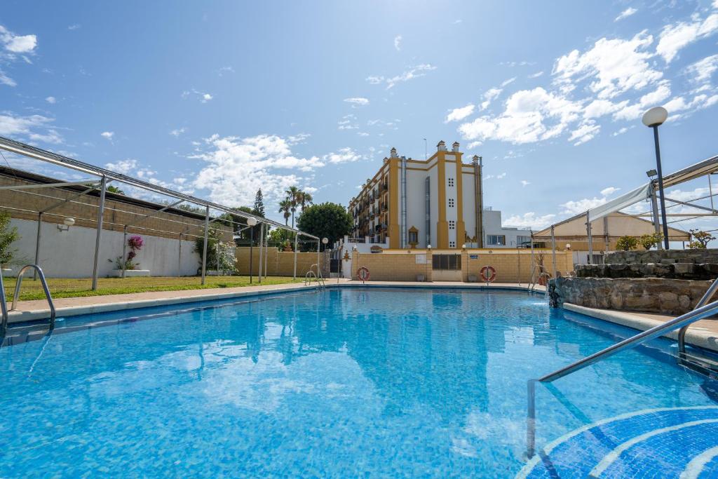 een groot blauw zwembad met een gebouw op de achtergrond bij Hotel Balneario de Chiclana in Chiclana de la Frontera