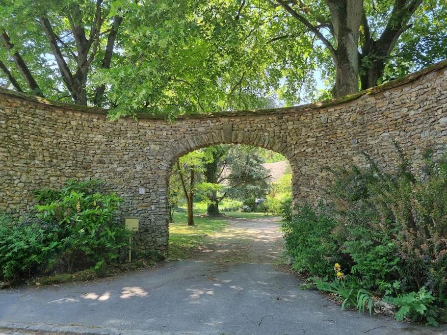 a brick wall with an archway in a park at La Parenthèse Campagnarde in Richarville
