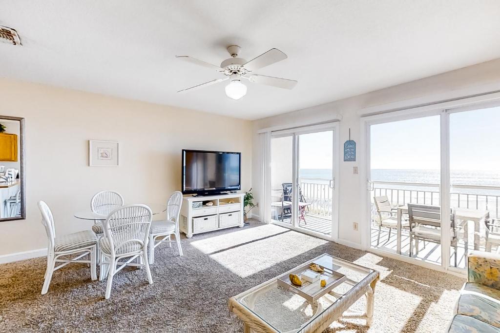 sala de estar con TV, mesa y sillas en Island Sands 306, en Fort Walton Beach