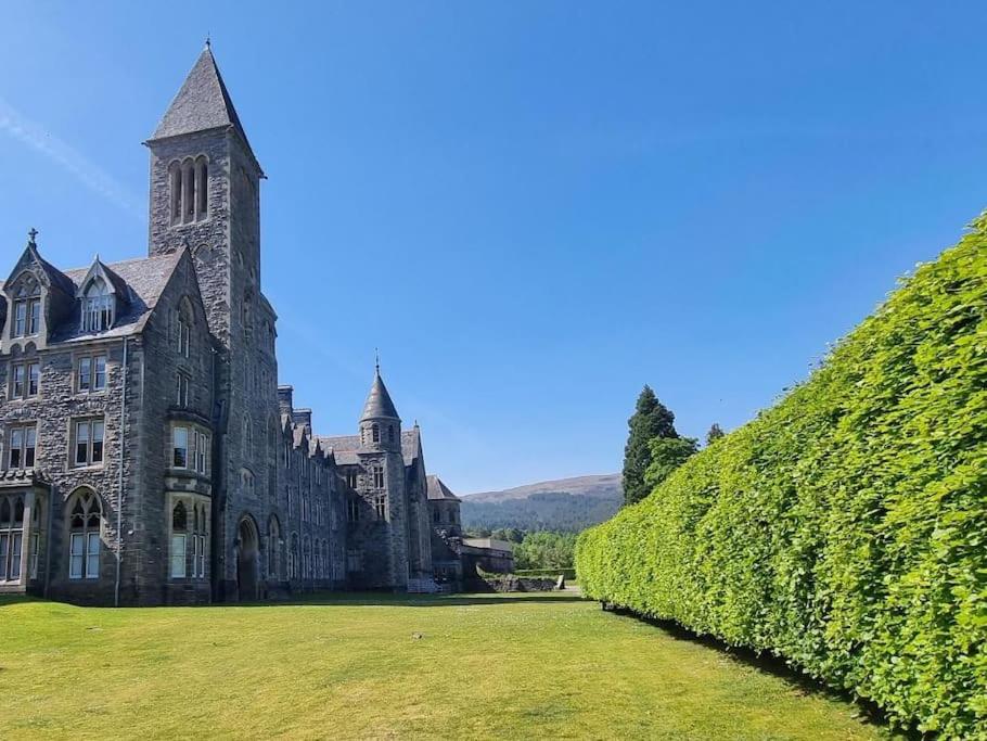 a large stone building with a green hedge at LOCH NESS - Luxury Highland Retreat in Scotland in Fort Augustus