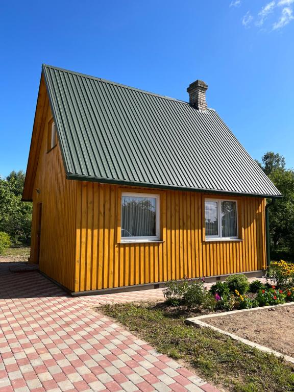 een klein geel huis met een gambrel dak bij Brīvdienu namiņš in Ludza