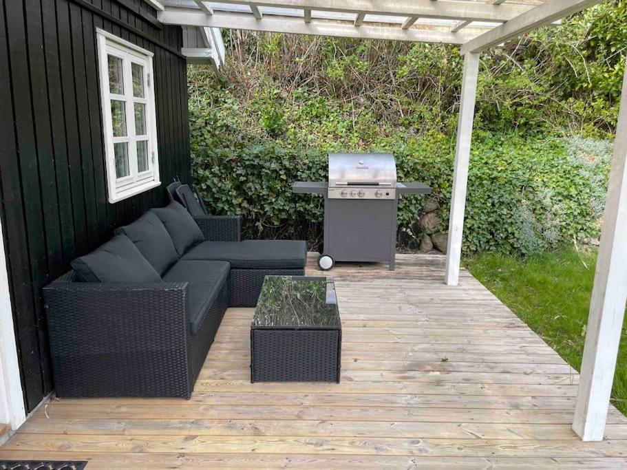 un patio con parrilla, sofá y mesa en Hyggeligt anneks på Thurø, tæt på vandet., en Svendborg