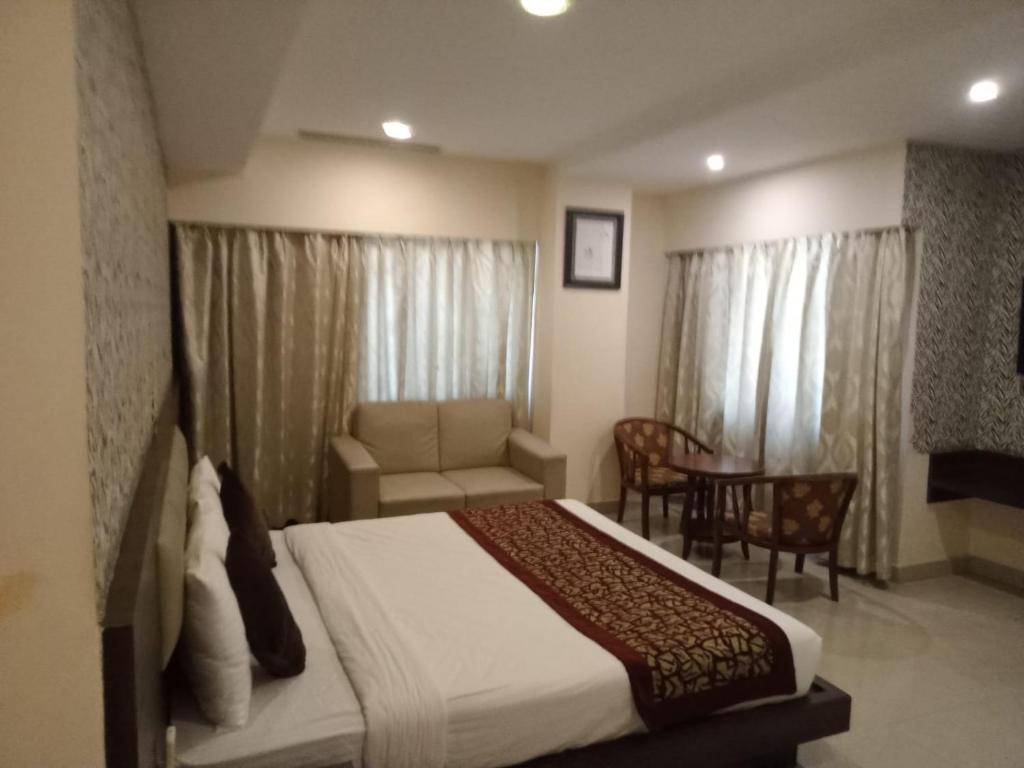 a bedroom with a bed and a couch and a table at The Contour Hotel in Guwahati