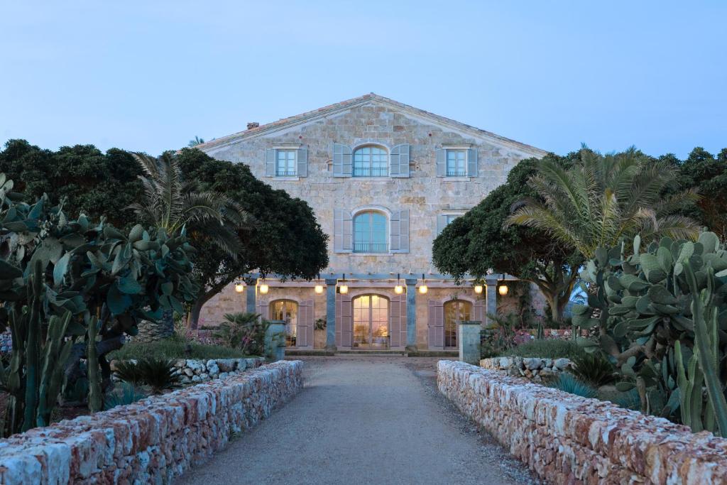 una grande casa in pietra con un sentiero in un giardino di Vestige Son Vell a Ciutadella