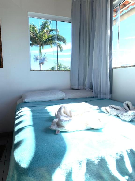 Un dormitorio con una cama y una ventana con una palmera en Bougainville Suítes, en Arraial do Cabo