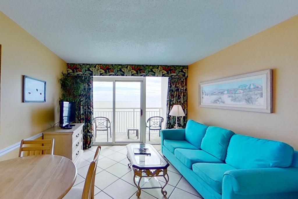 a living room with a blue couch and a table at Camelot by the Sea 1804 in Myrtle Beach