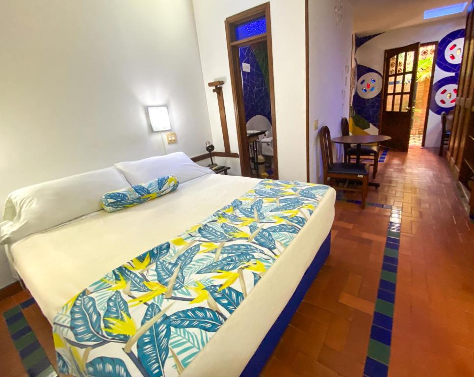 a bedroom with a bed with a colorful blanket on it at Hotel Casa Santa Monica Norte in Cali