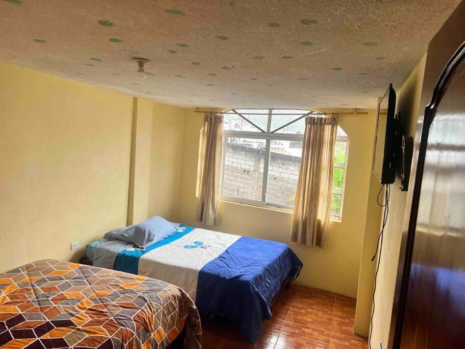 um quarto com uma cama e uma janela em Ventana al Pedacito de Cielo em Baños