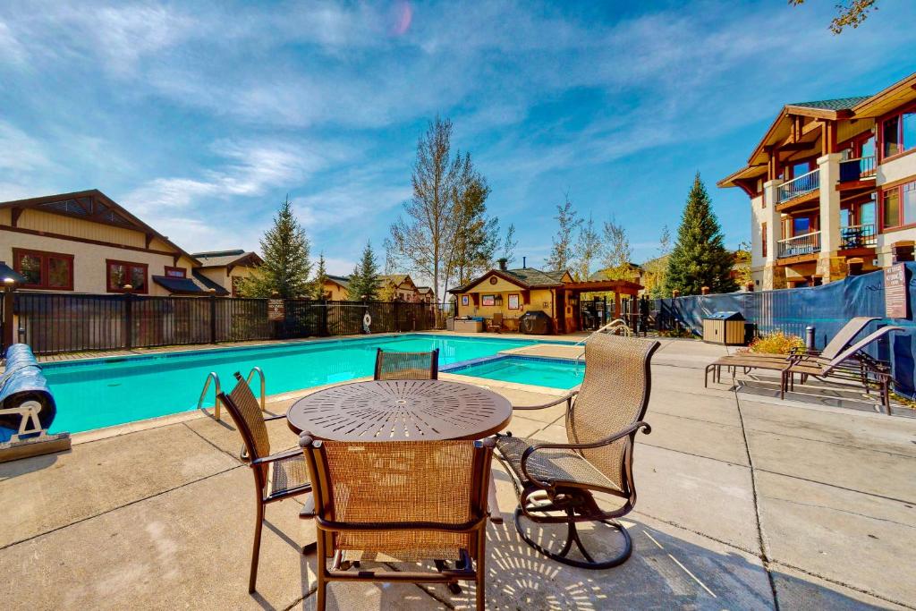 Un patio con mesa y sillas junto a una piscina. en EagleRidge Lodge 200, en Steamboat Springs