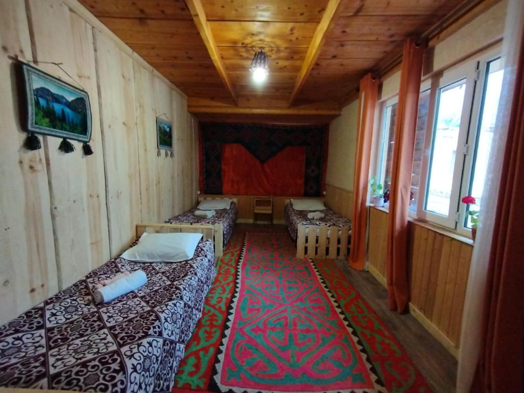 een kleine kamer met 2 bedden en een tapijt bij Guest house CBT Chon-Kemin in Shabdan