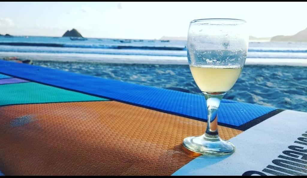 a glass of wine sitting on a table near the ocean at Mahkota Atia Bungallow in Praya
