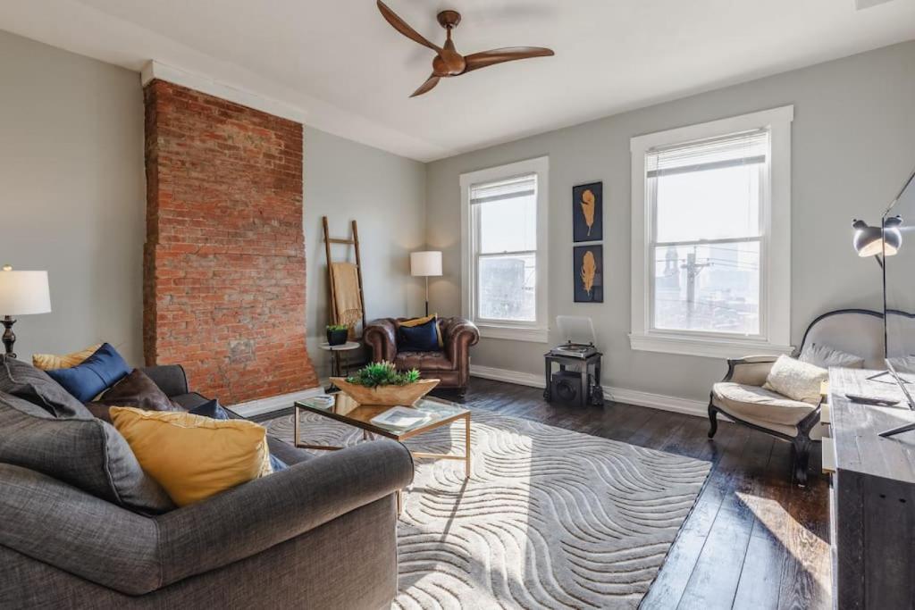 a living room with a couch and a brick wall at OTR Penthouse Walk Everywhere FREE Parking in Cincinnati