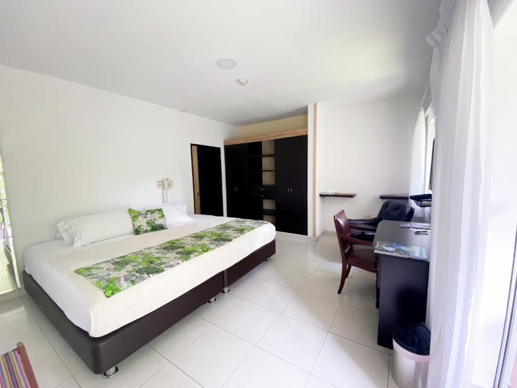 a bedroom with a bed and a desk in a room at Hotel Campestre Santa Monica Pance in Cali