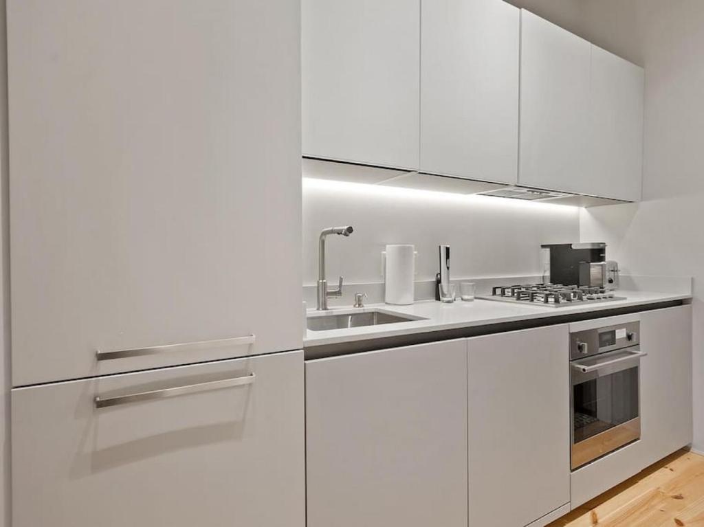 a white kitchen with white cabinets and a sink at Over the Rhine Luxury MicroSuite On Findlay Market in Cincinnati