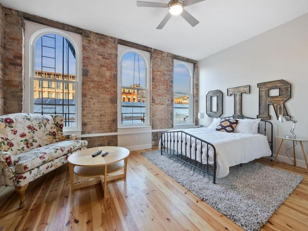 ein Schlafzimmer mit einem Bett, einem Sofa und Fenstern in der Unterkunft Findlay Suites Explore OTR with an Outdoor Deck in Cincinnati