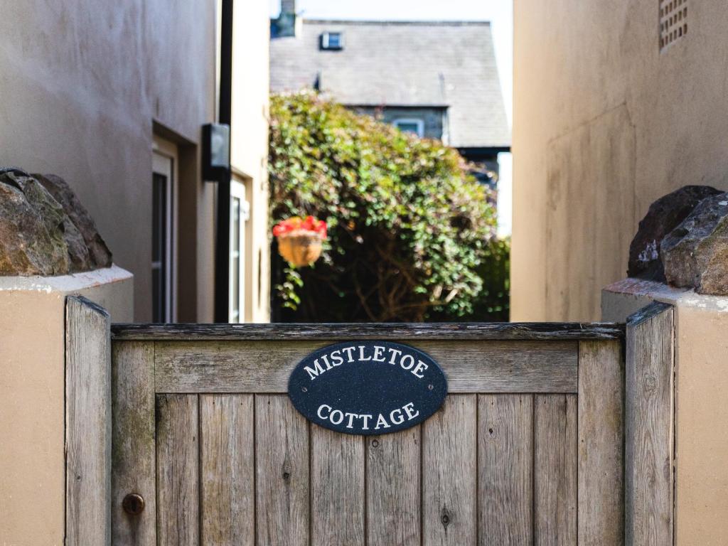 a sign on a wooden fence in front of a building at Mistletoe Cottage in Bamburgh