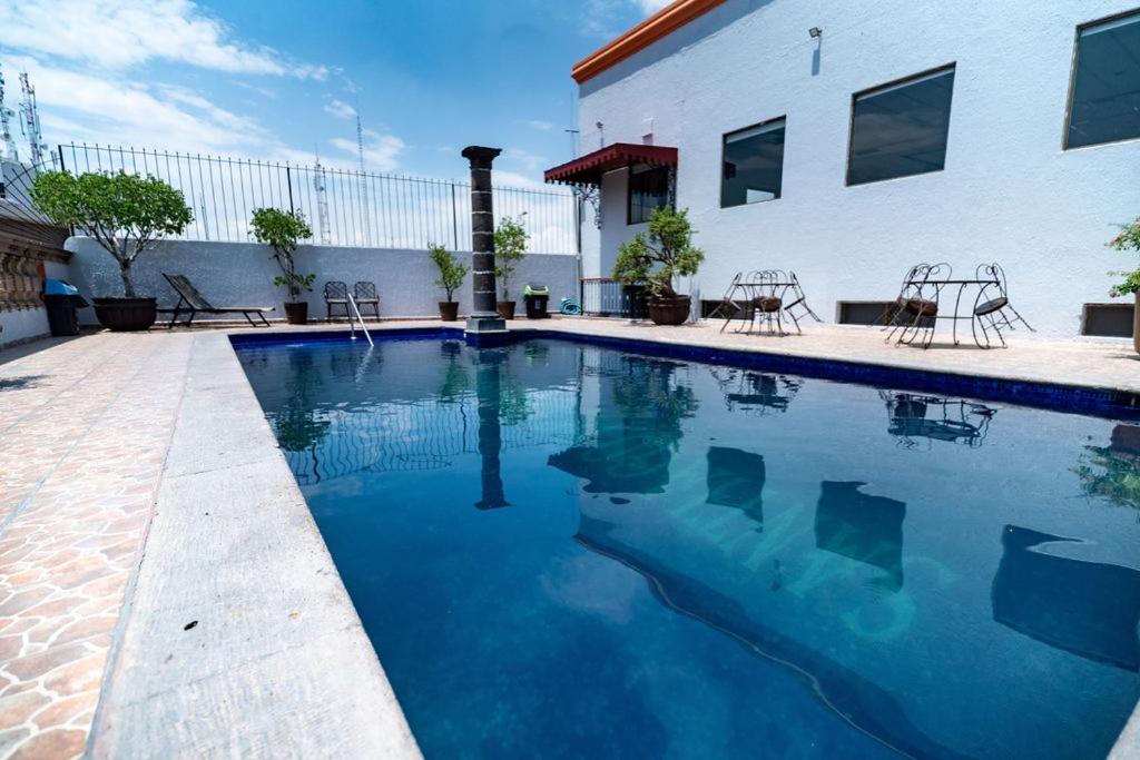 a swimming pool with blue water in front of a building at Hotel Santiago De Compostela - Guadalajara Centro Historico in Guadalajara