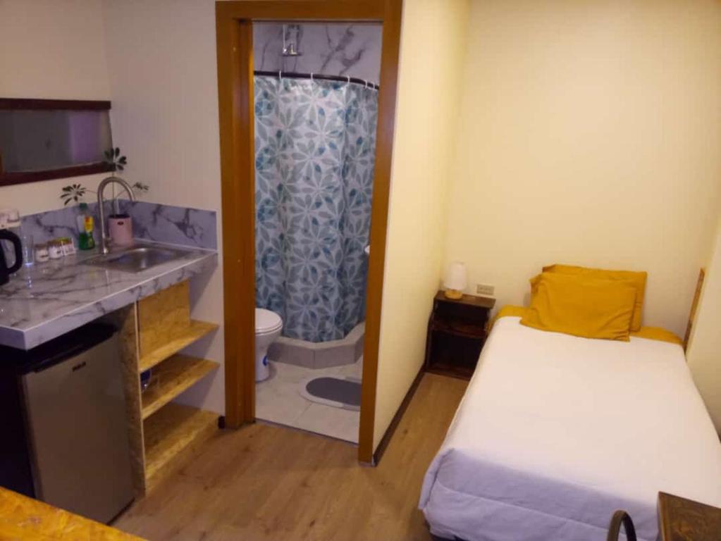 Habitación pequeña con cama y baño con ducha. en Casa de Huéspedes Tu Parada en Cuenca, en Cuenca