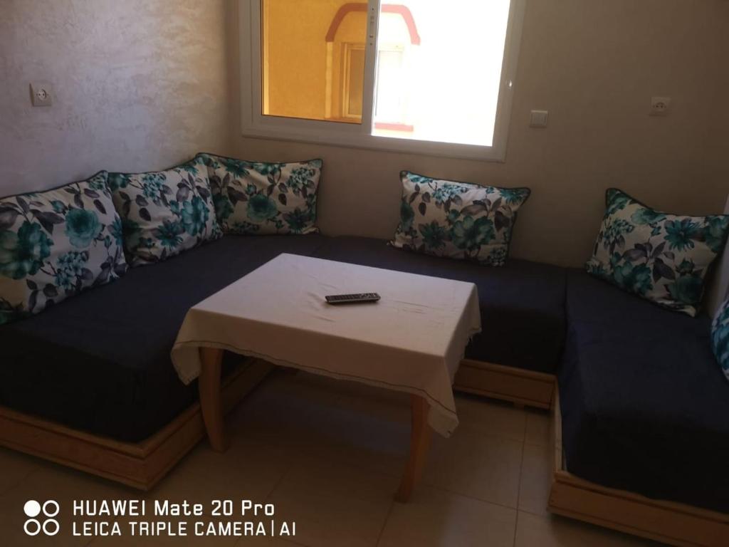 un sofá con mesa en una habitación en Appartement à louer wadie en Fnidek