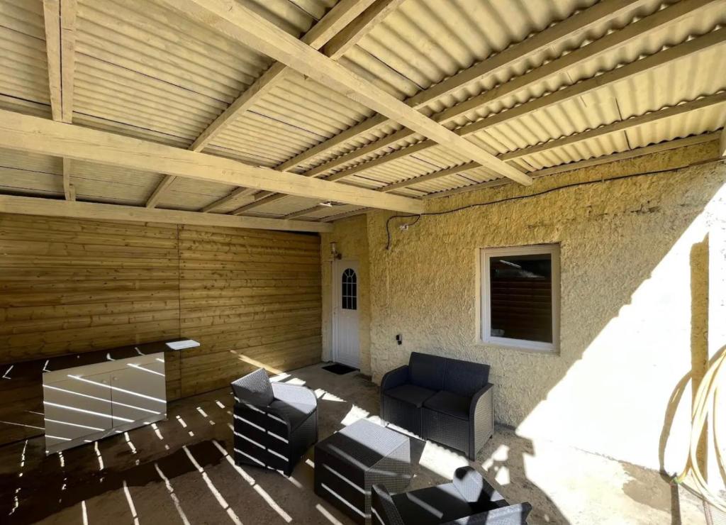 sala de estar con techo de madera y sillas en Charmant studio avec terrasse en Château-lʼÉvêque