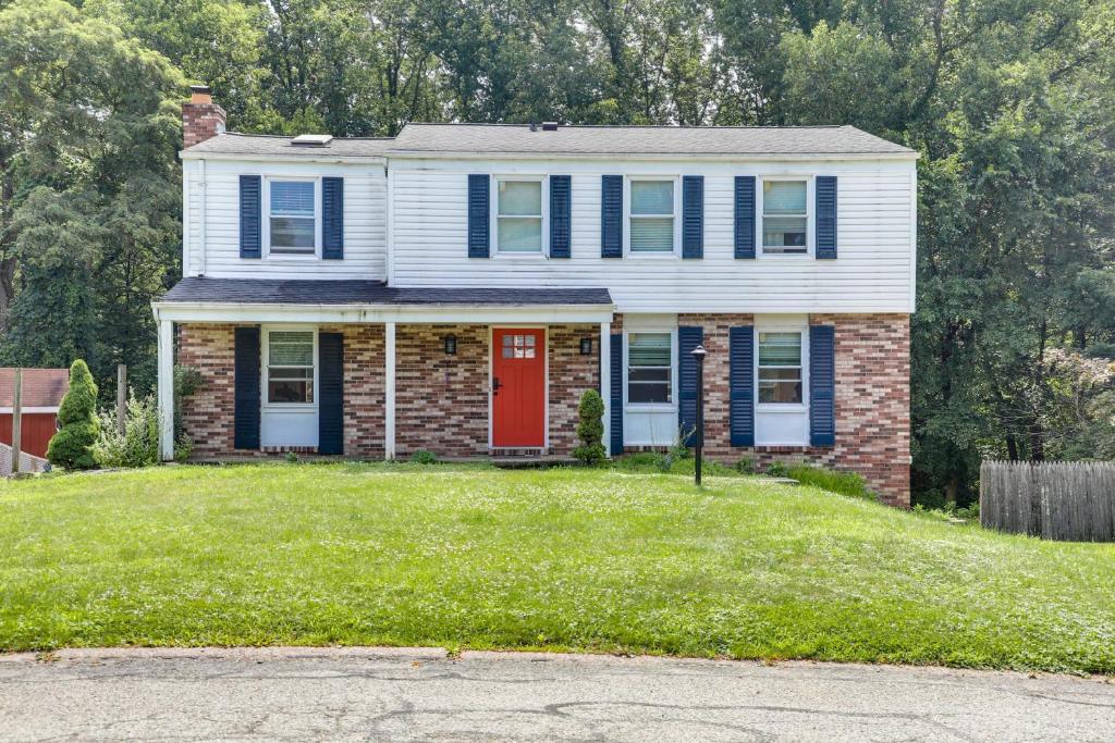 a house with a red door on a green yard at Charming Vacation Rental 15 Mi to Pittsburgh in Monroeville