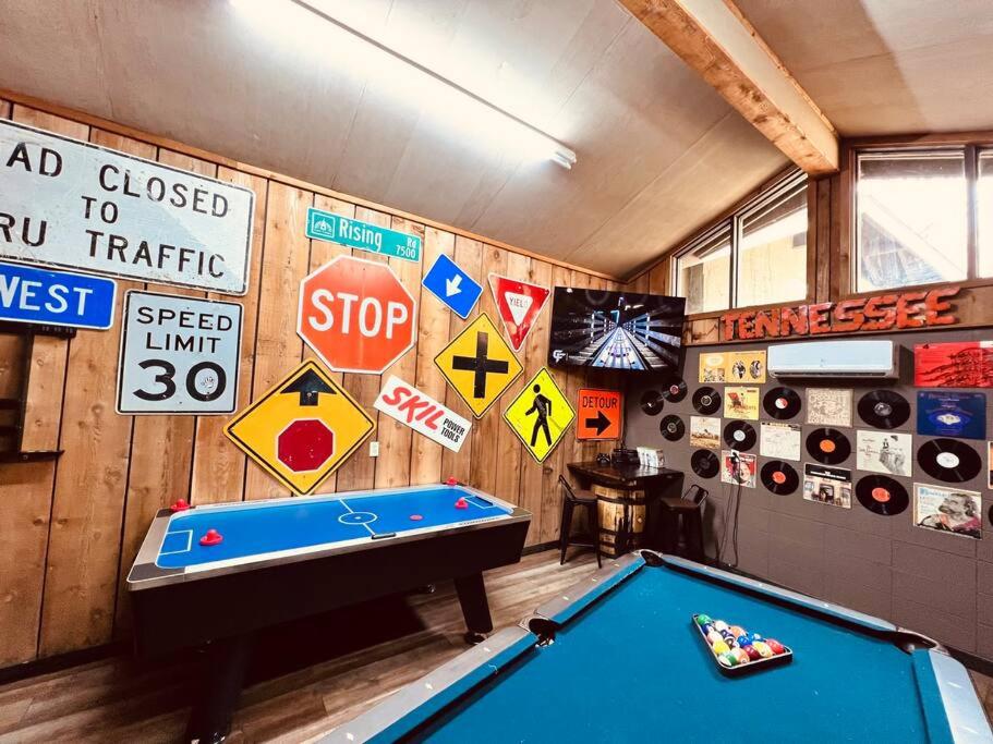 ein Zimmer mit einem Billardtisch und Schildern an der Wand in der Unterkunft Bourbon Hollow Lodge with Hot Tub and Pool plus Game Room only 5 min to downtown in Gatlinburg