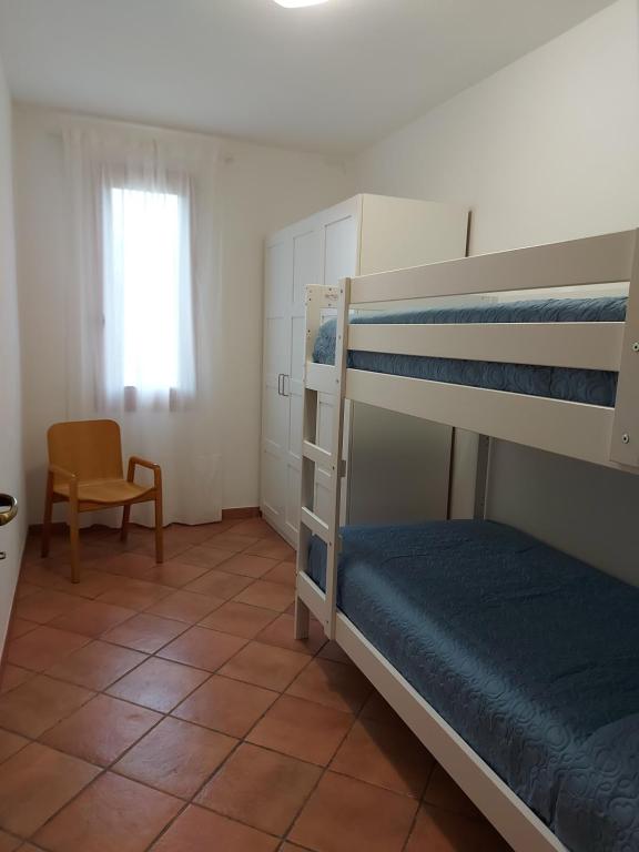 una camera con 2 letti a castello e una sedia di Casa Gio' IUN R4246 a Solanas