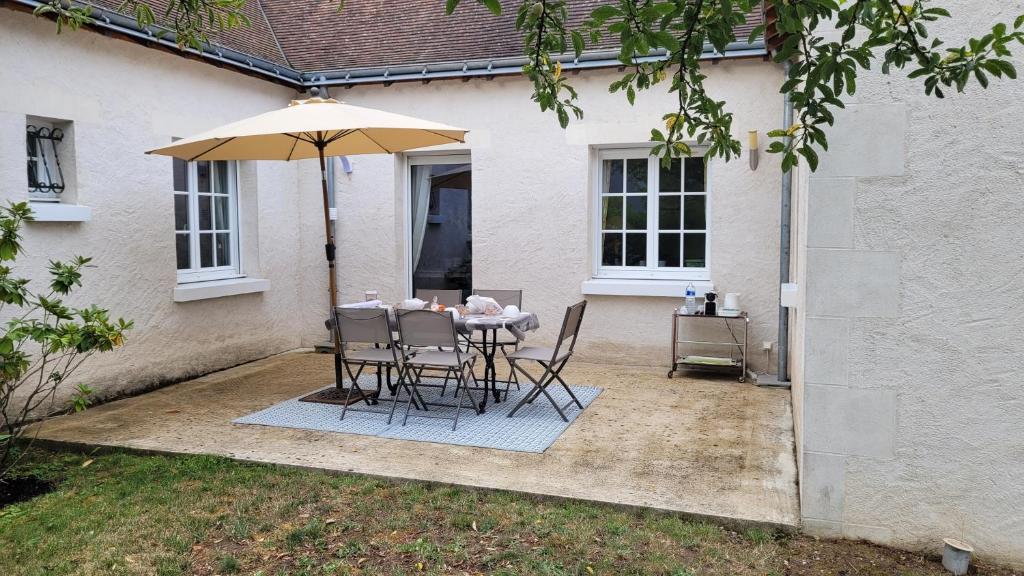 een tafel en stoelen onder een paraplu in een tuin bij La rocaille 3 chambres doubles in Fondettes