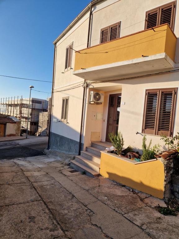 una casa bianca con una porta gialla e scale di Mari e Monti a Scano Montiferro