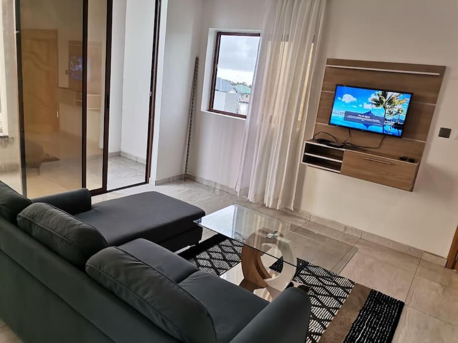 ein Wohnzimmer mit einem Sofa und einem TV in der Unterkunft Studio de luxe chez FOUR IN ONE Résidence in Limbe