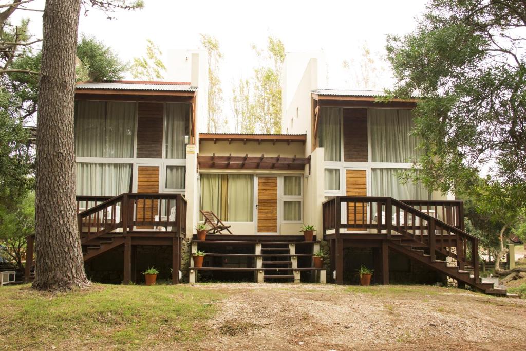 una casa con dos cubiertas y un árbol en Cabañas Sottobosco en Las Gaviotas