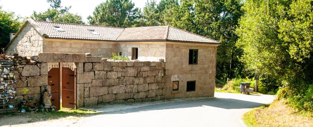 un edificio de piedra con una puerta y una pared de piedra en Casa D'Mina, en Redondela