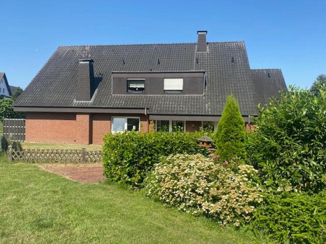 a house with a black roof and some bushes at In der Heide in Löhne