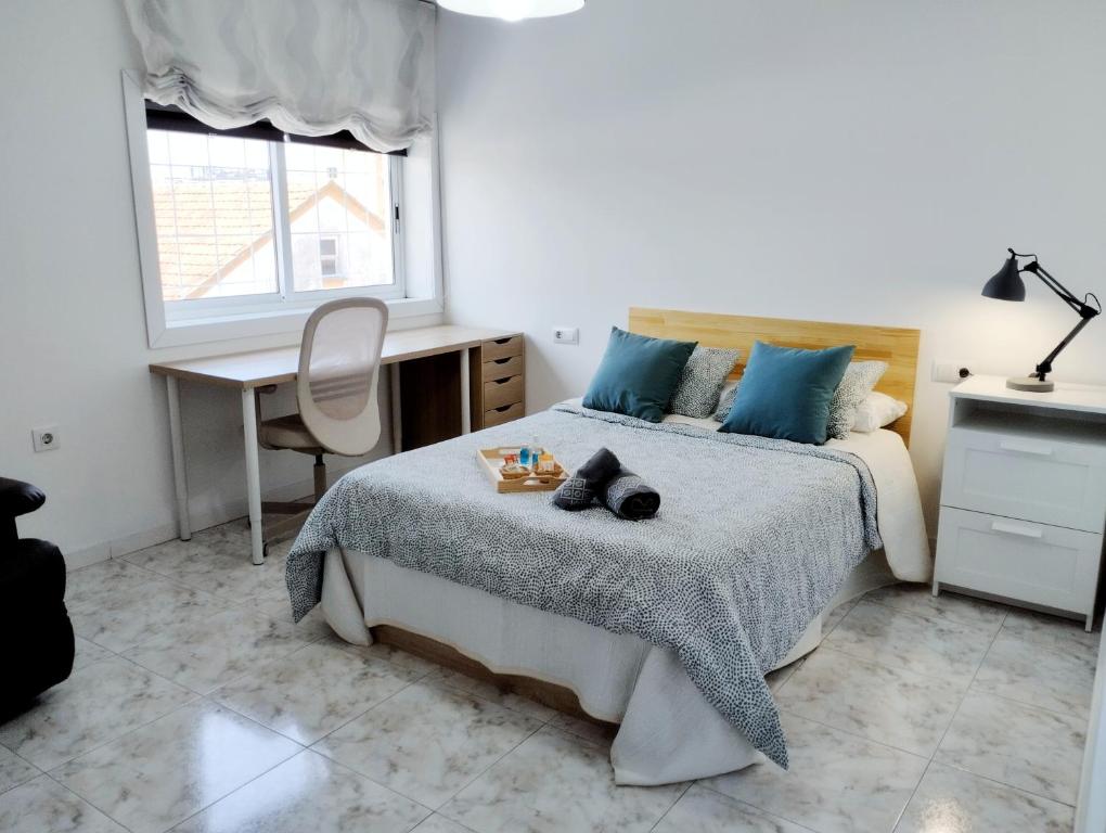 um quarto com uma cama, uma secretária e uma janela em Amplio piso de confort. em Vigo