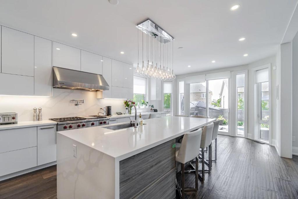 a kitchen with white cabinets and a large white island at Poolside Perfection, Culinary Delight in Mississauga