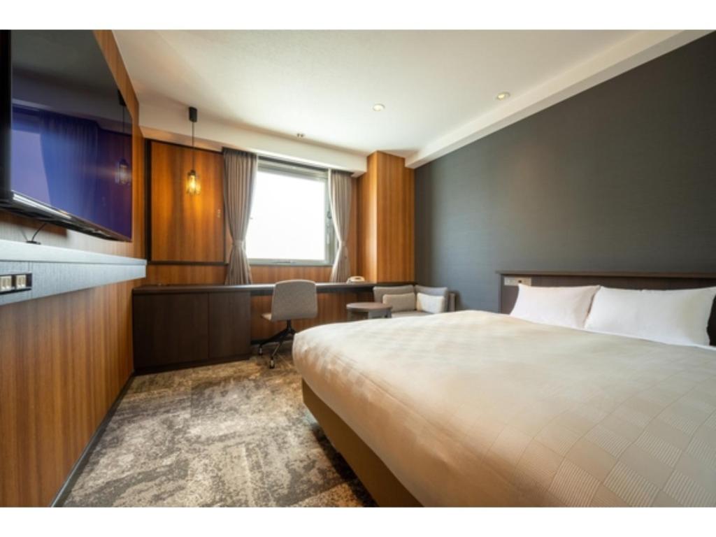una camera d'albergo con un grande letto e una scrivania di Misawa City Hotel - Vacation STAY 81764v a Misawa