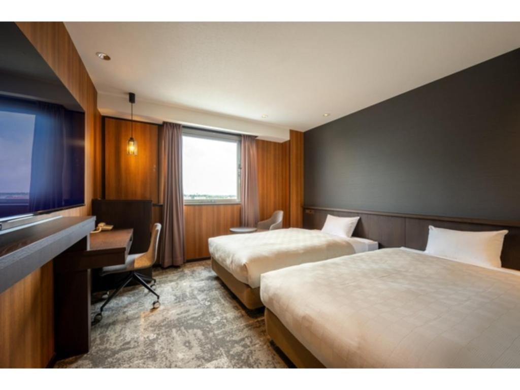 Misawa City Hotel - Vacation STAY 81776v في ميساوا: غرفة فندقية بسريرين ومكتب وتلفزيون