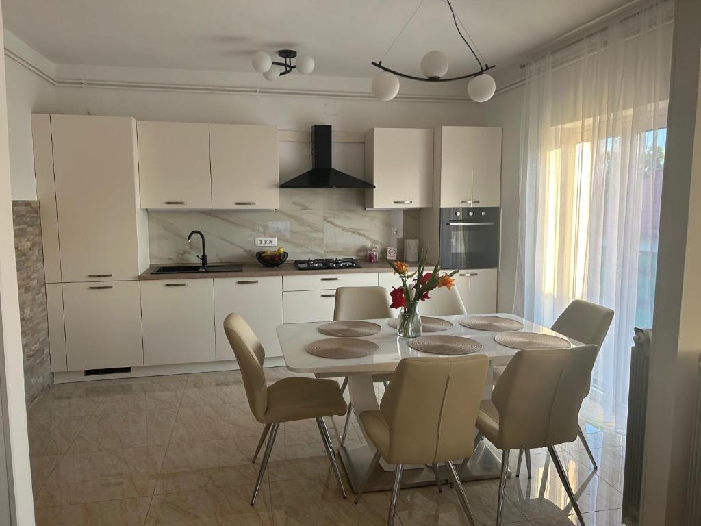 una cocina con mesa y sillas y una cocina con armarios blancos. en Deluxe apartman Mimi, en Viskovo