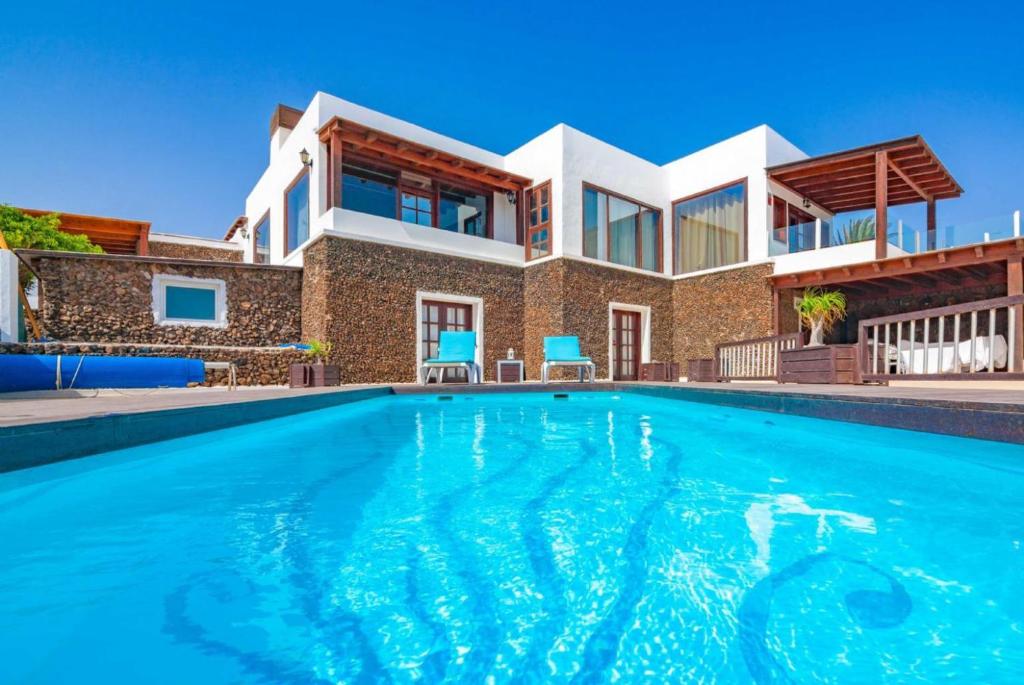 a house with a swimming pool in front of a house at Villa Vista Mar in Yaiza