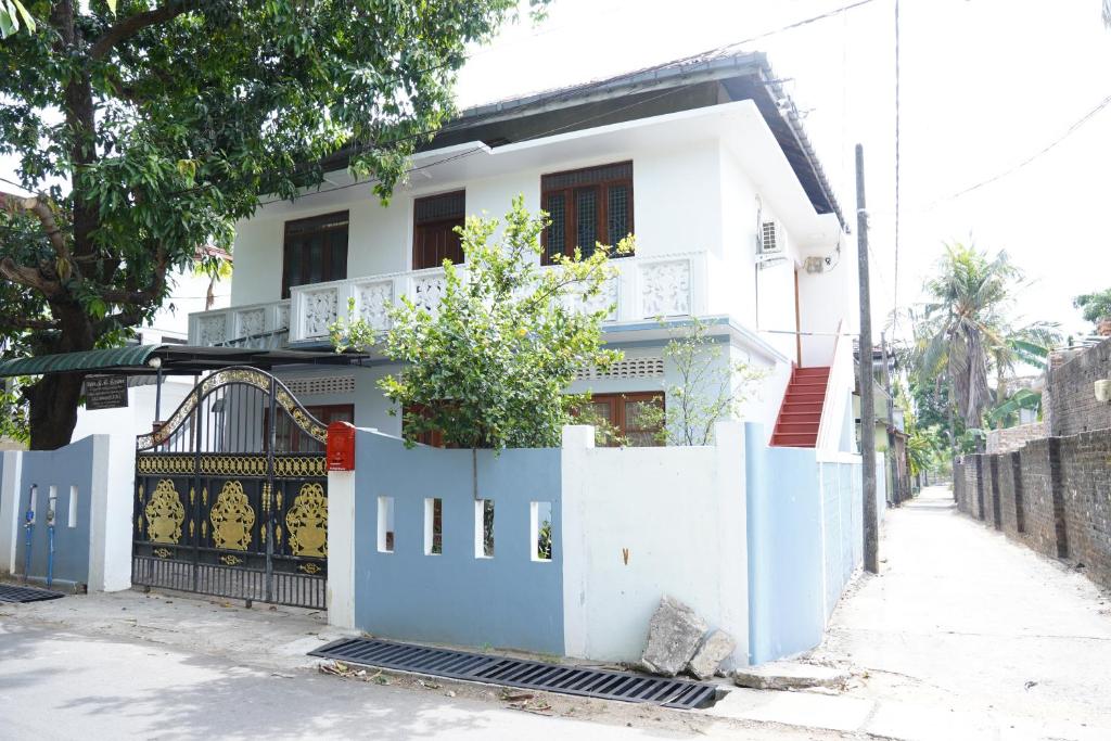 una casa blanca con una valla azul delante de ella en Nilo's Guest House en Batticaloa