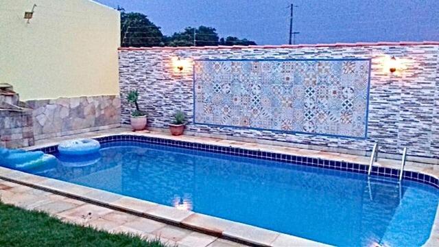 a swimming pool in front of a brick wall at Vila agradável e confortável com piscina in Pirenópolis