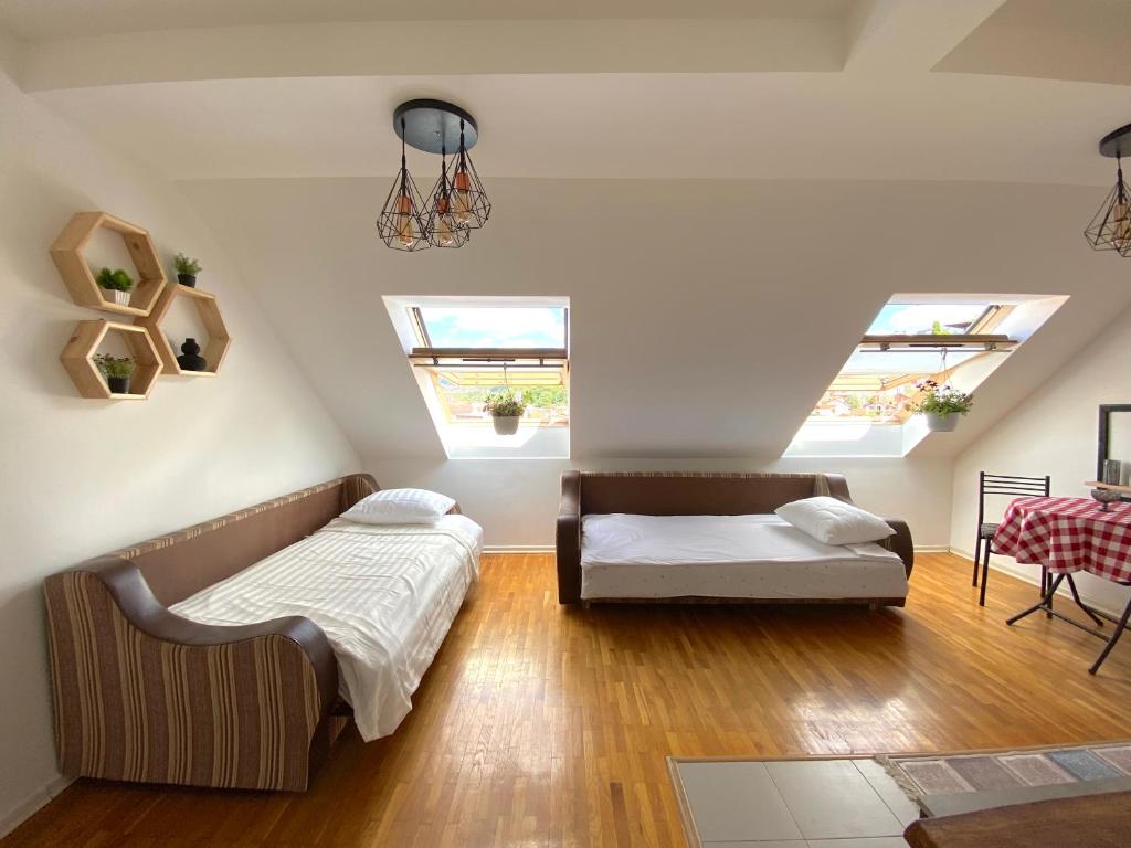 a attic bedroom with two beds and a couch at KENT Apartments in Prishtinë