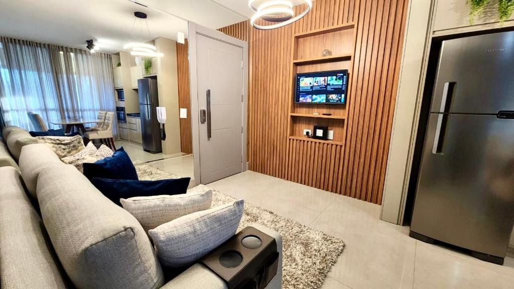 a living room with a couch and a tv at Estúdio Luxuoso no Vertigo com Smart TV na Cama in Campo Grande