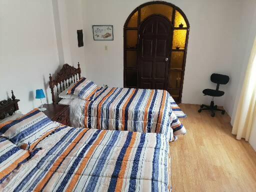 1 dormitorio con 2 camas y 1 silla en SAN PAOLY., en Trujillo