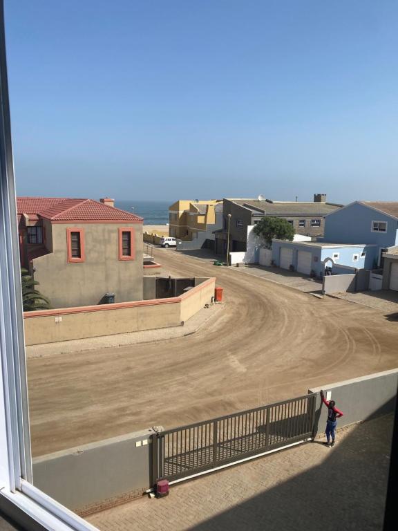 a person standing on a balcony looking at a dirt road at Riekert's Self-Catering Apartment @Silver Sands in Swakopmund