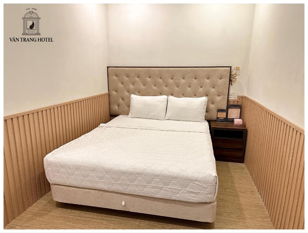 a bedroom with a bed and a nightstand with a white mattress at Vân Trang Hotel in Vĩnh Long