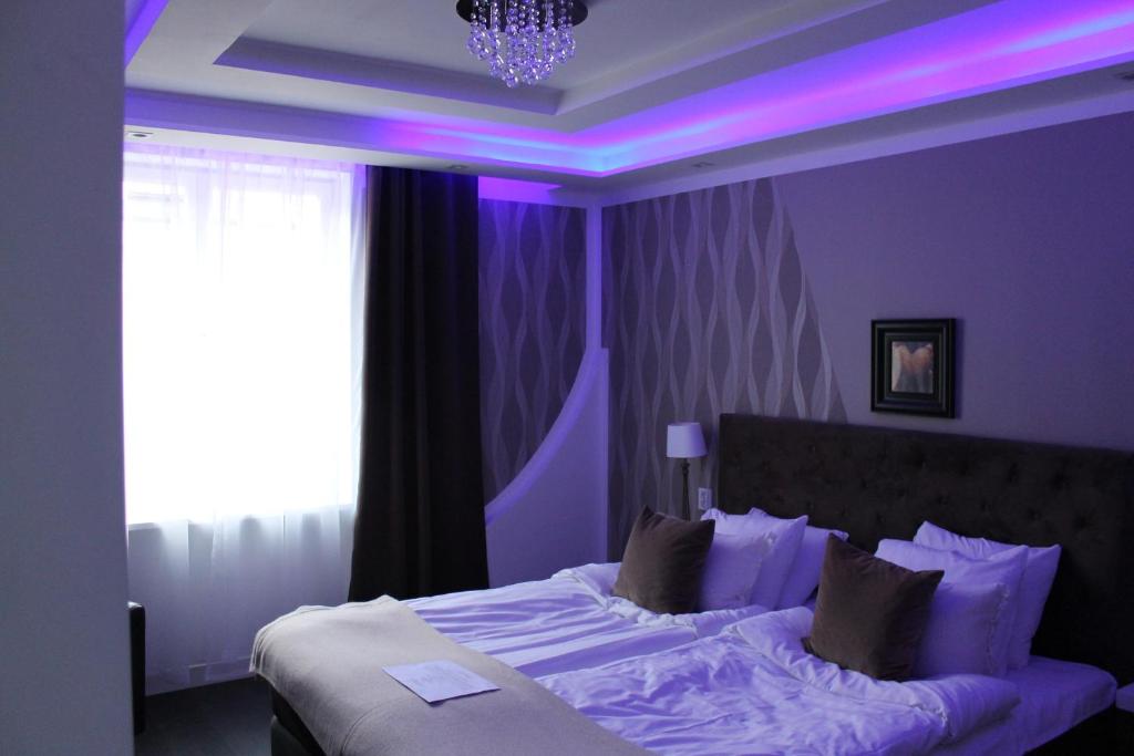 Skänninge stadshotell في Skänninge: غرفة نوم أرجوانية مع سرير مع إضاءة أرجوانية