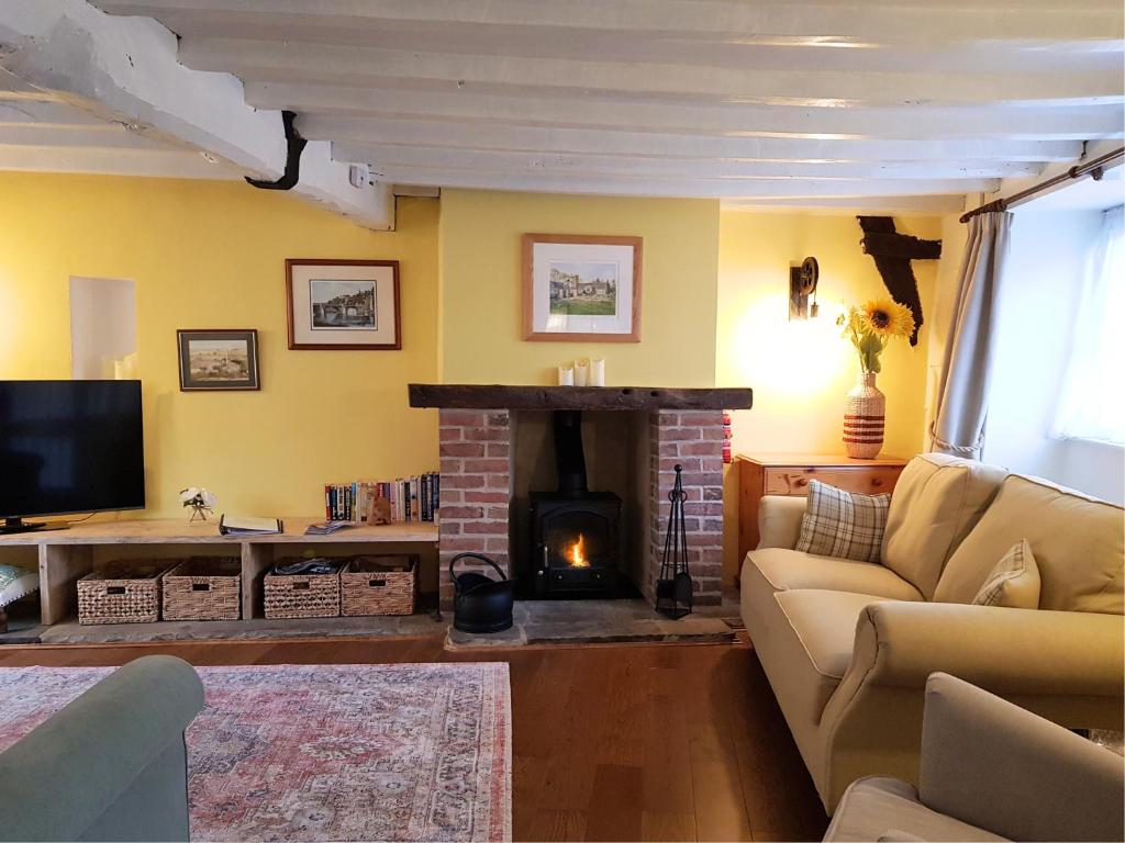 sala de estar con sofá y chimenea en Cruck Cottage, en Pickering