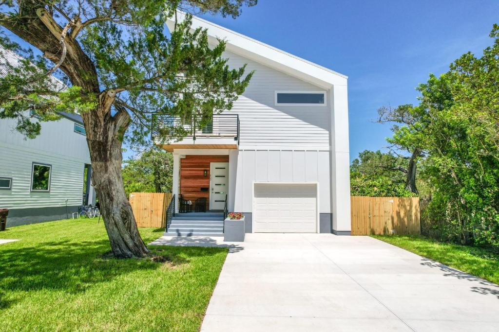 a white house with a tree next to a sidewalk at Davis Shores Lookout- Dog Friendly Mins to DNTN & Beach in Saint Augustine