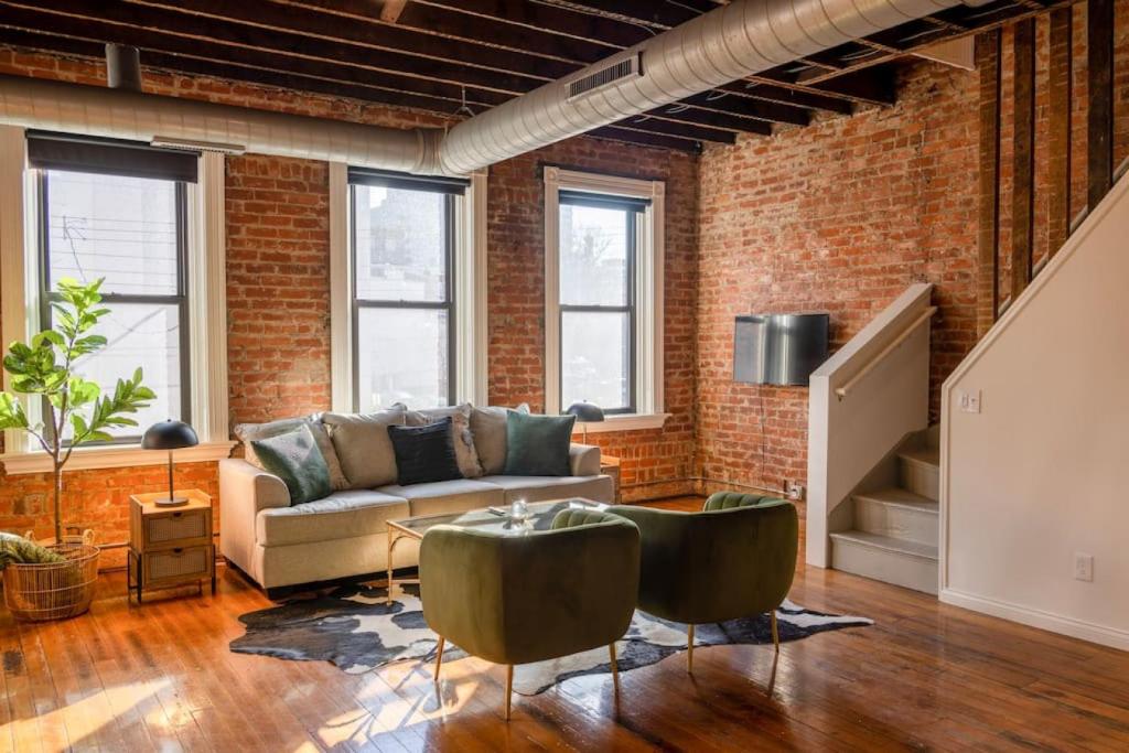 a living room with a couch and a brick wall at Spacious Retreat w Private Roof Deck Walkable to ALL in Cincinnati